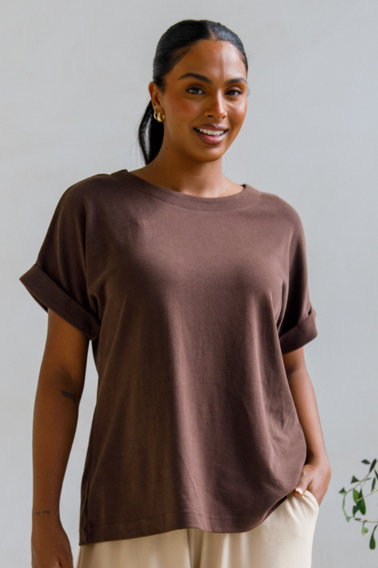 A woman wearing a chocolate brown lounge top with batwing sleeves and a scoop neckline, paired with light beige pants.
